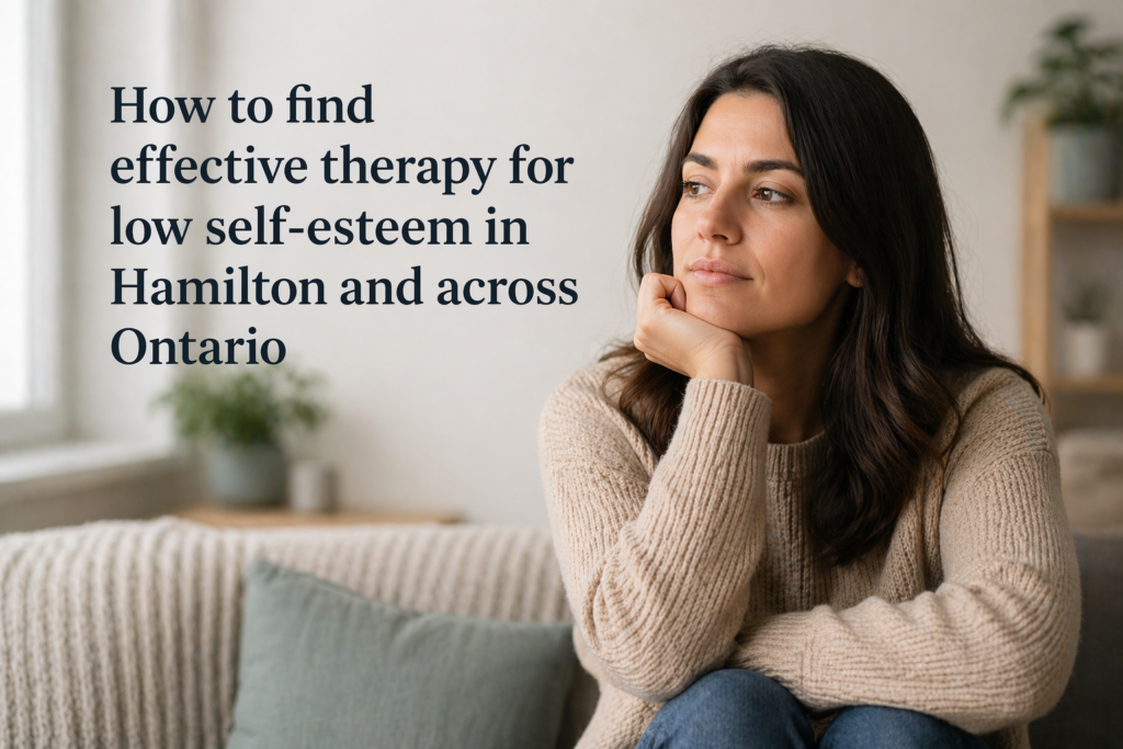 A thoughtful woman sits on a sofa in a softly lit, neutral-toned room, resting her chin on her hand and gazing off calmly. The setting feels warm and modern with minimal décor, while text beside her reads “How to find effective therapy for low self-esteem in Hamilton and across Ontario.”