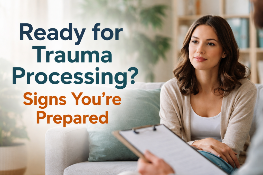 A calm, well-lit therapy setting with a woman seated on a couch speaking to a therapist holding a clipboard. Overlaid text reads, “Ready for Trauma Processing? Signs You’re Prepared